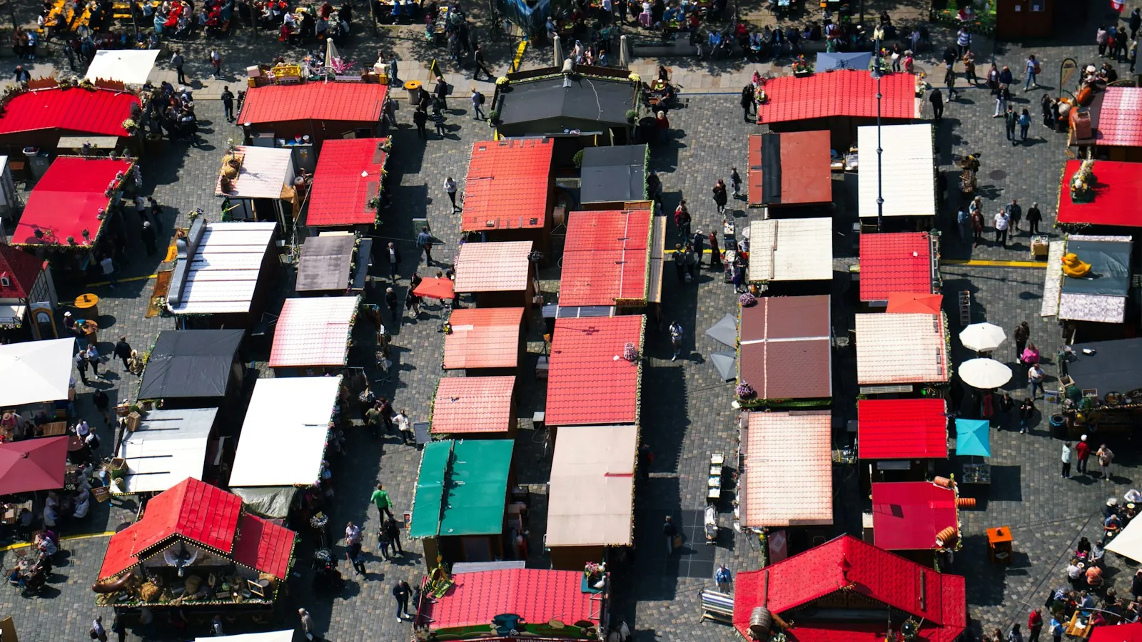 Aerial view of a market square filled with rows of red, white and green stall roofs